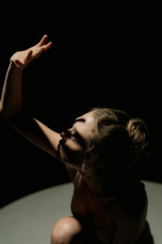 a naked woman sitting on top of a table, a portrait, by David Donaldson, unsplash, light and space, contemporary dance, hands raised, square, moonlit