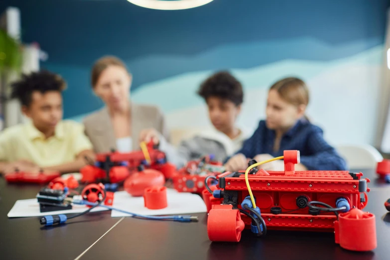a group of children sitting around a table playing with legos, by Adam Marczyński, pexels contest winner, danube school, red blue theme, avatar image, robotic arms, 8k octae render photo