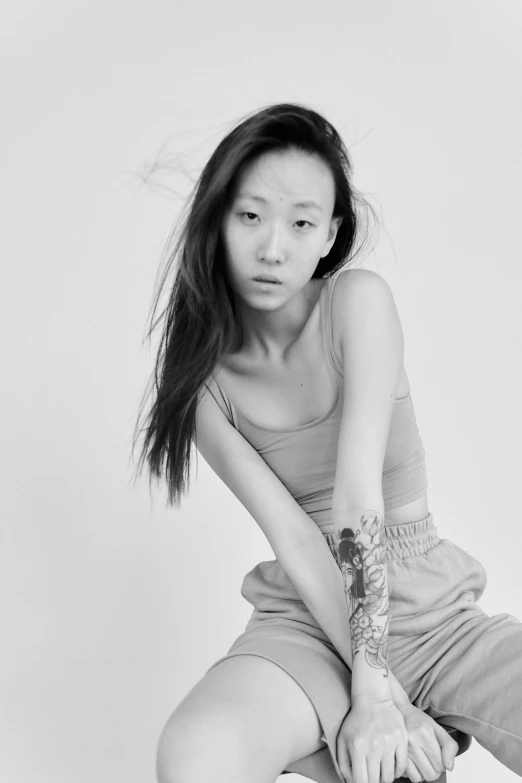 a woman sitting on top of a suitcase, a black and white photo, inspired by Kim Tschang Yeul, wearing a track suit, gray skin. grunge, jaeyeon nam, headshot profile picture