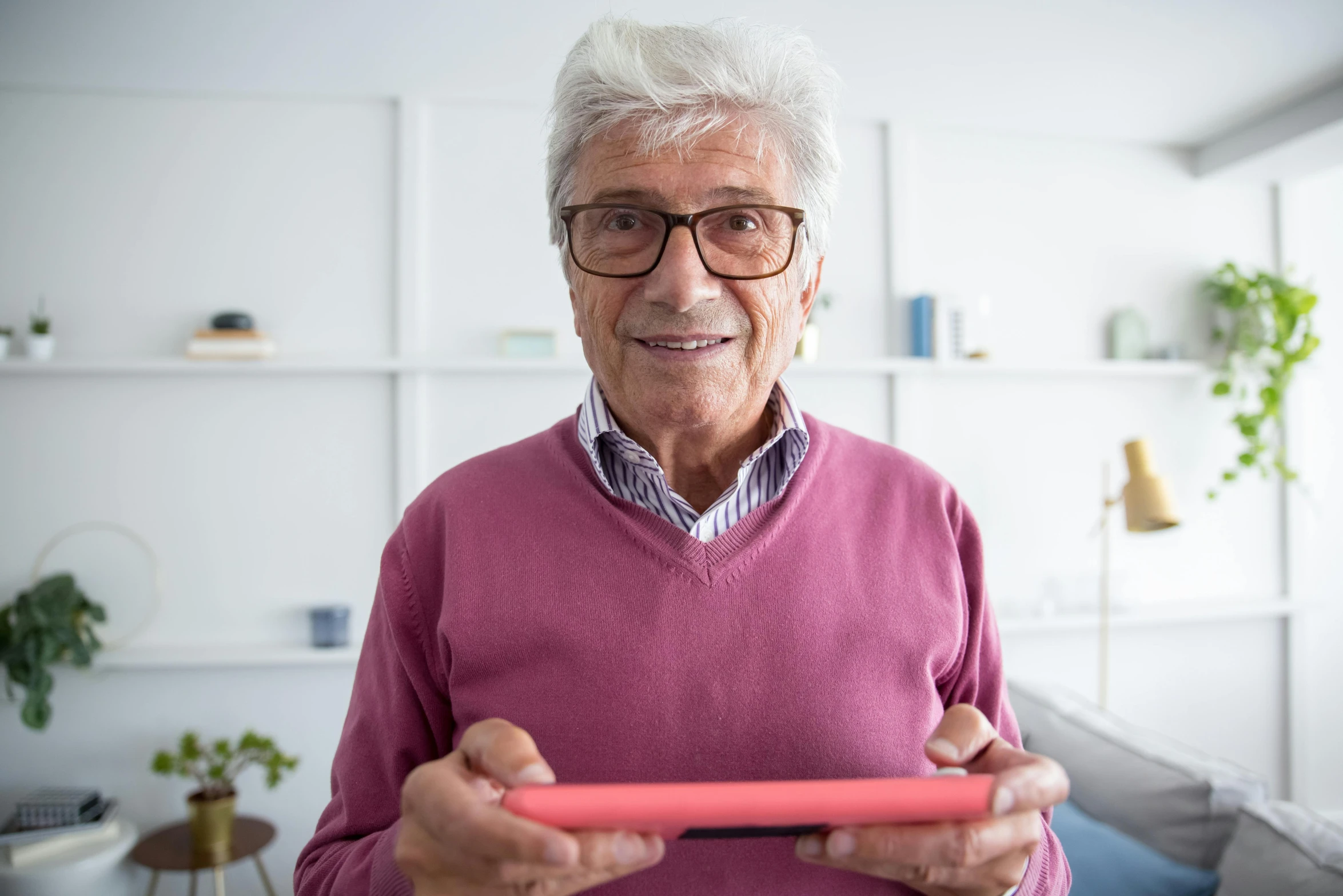 a close up of a person holding a nintendo wii controller, pexels contest winner, figuration libre, dark grey haired man, wearing square glasses, using a magical tablet, smiling at camera