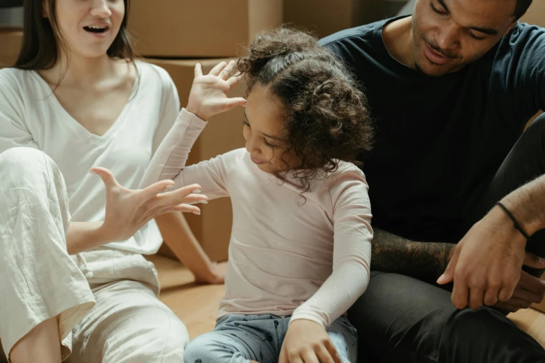 a man and woman sitting on the floor with a child, greeting hand on head, te pae, mental health, wavy hair spread out