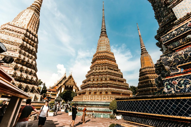 a group of people walking down a street next to tall buildings, thai architecture, cathedrals, profile image