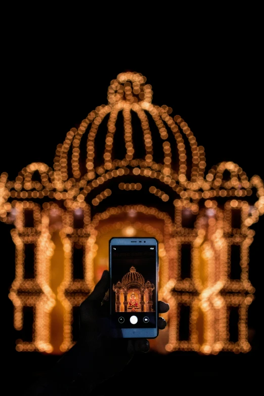 a person taking a picture of a building with christmas lights, standing in a hindu kovil, screensaver, photographed for reuters, museum light