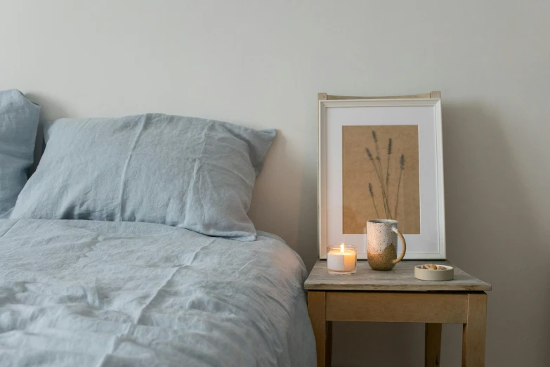 a bed room with a neatly made bed and a picture on the wall, by Helen Stevenson, featured on pinterest, holding a candle holder, light grey blue and golden, linen, short light grey whiskers