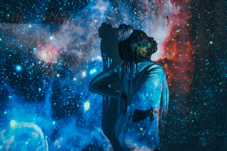 a man with dreadlocks standing in front of a galaxy, a hologram, by Julia Pishtar, pexels contest winner, afrofuturism, girl looks at the space, ☁🌪🌙👩🏾, out of body experience, her back is to us