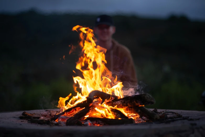 a man that is sitting in front of a fire, by Jessie Algie, pexels contest winner, setting in nature, avatar image, close - up photograph, commercial photo