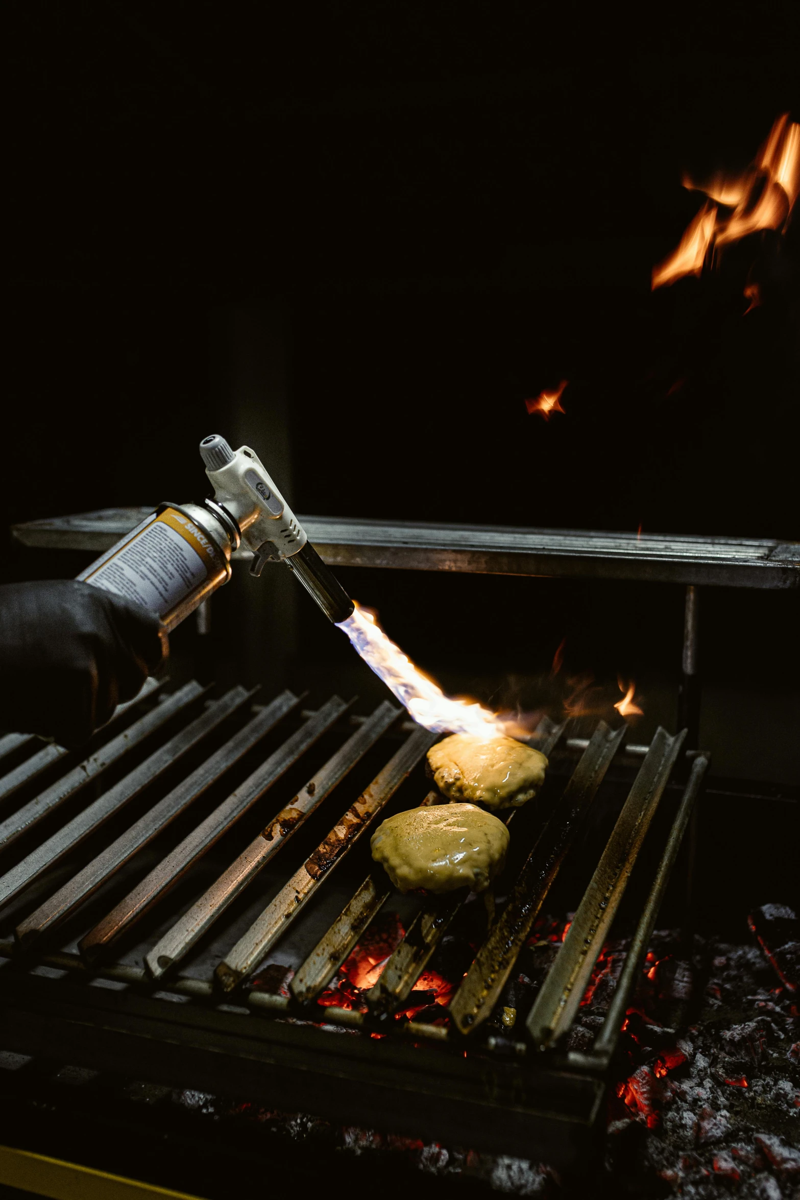 a person is cooking a hamburger on a grill, by Adriaen Hanneman, unsplash, auto-destructive art, welding torches for arms, with a black background, molecular gastronomy, grilled artichoke