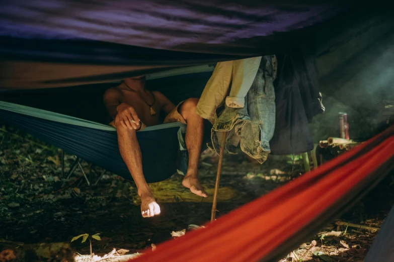 a man laying in a hammock in the woods, by Jessie Algie, worksafe. instagram photo, inside a gang hideout, multi colour, 8 k film still