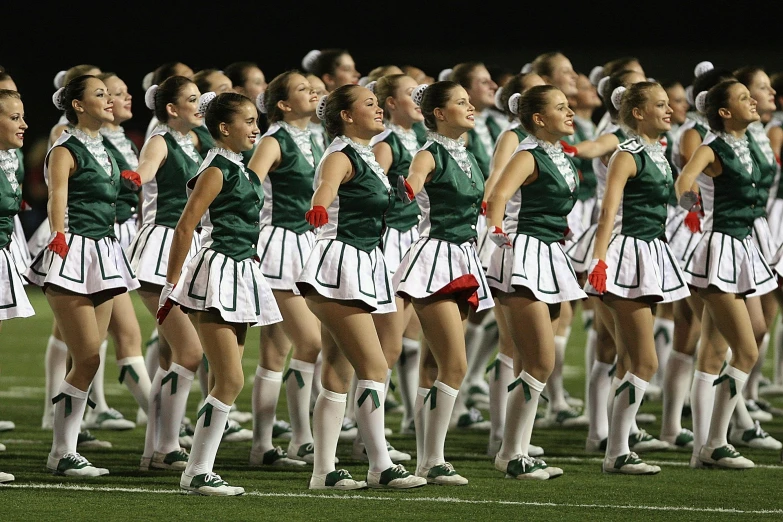 a group of women standing next to each other on a field, an album cover, by Ben Zoeller, reddit, antipodeans, teal uniform, jets, in 2 0 1 2, performing