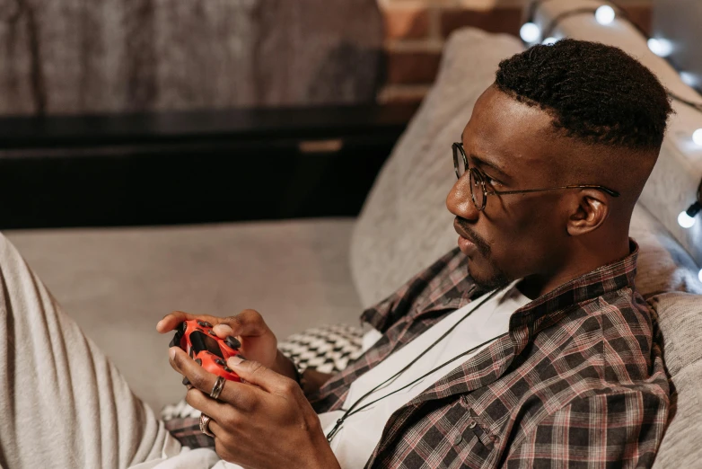 a man sitting on a couch playing a video game, trending on pexels, ( ( dark skin ) ), gordon freeman, nintendo game, phone in hand