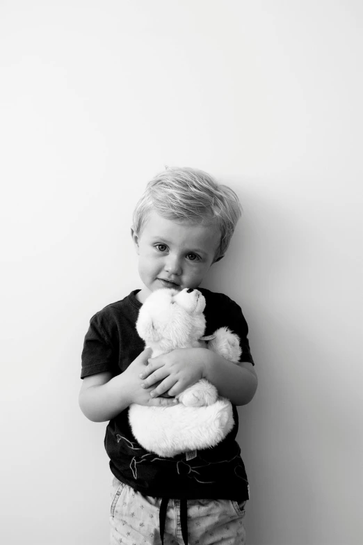 a black and white photo of a young boy holding a teddy bear, by Marc Bell, pexels contest winner, minimalism, small blond goatee, a handsome, kid a, miffy