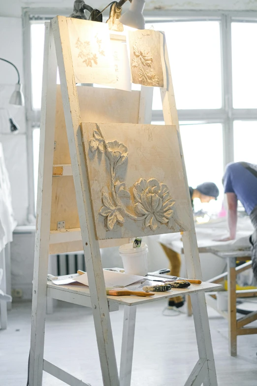 a man that is standing in front of a easel, a silk screen, inspired by ferdinand knab, behance, carved in white marble, botanical, professional woodcarving, fashion studio