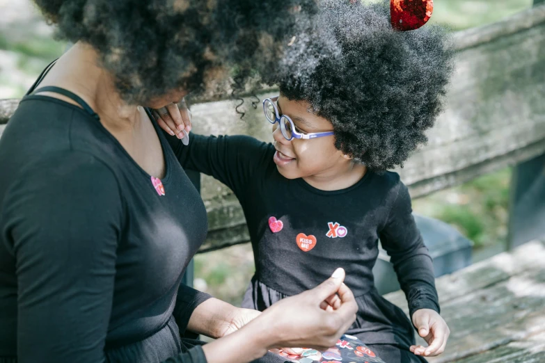 a woman sitting next to a little girl on a bench, black jewellery, nerdy black girl super hero, hearts, families playing