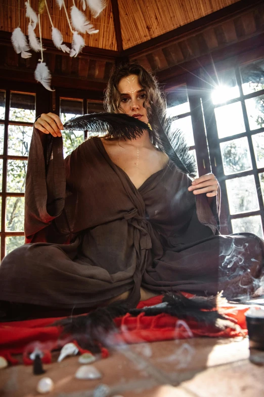 a woman sitting on top of a bed next to a window, inspired by Artemisia Gentileschi, renaissance, feather suit, emma watson vietnam door gunner, occult robes, intense smoldering