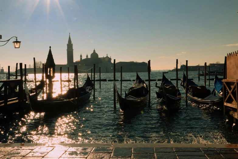 a group of gondolas sitting on top of a body of water, a picture, late afternoon sun, profile image, in the sun, slide show