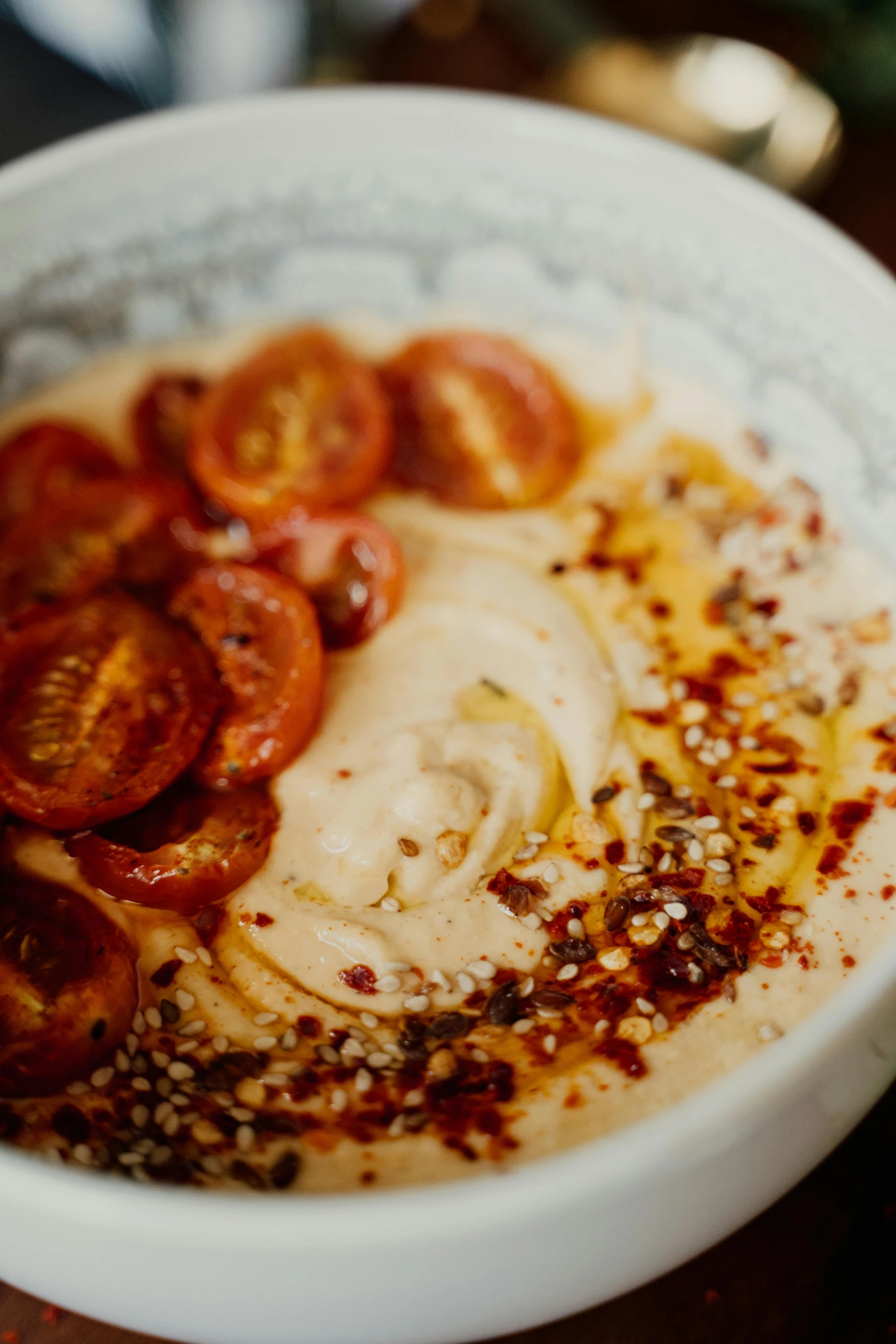 a close up of a bowl of food on a table, by Sam Dillemans, also one tomato slice, humus, caramel, spots