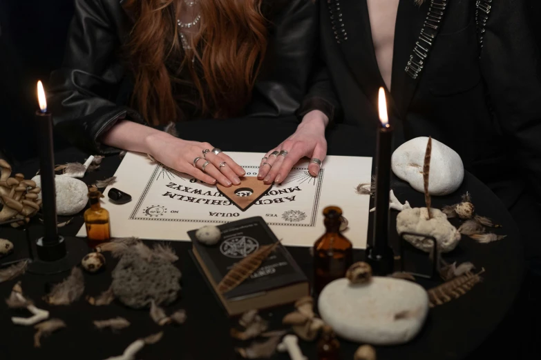 a couple of people that are sitting at a table, an album cover, trending on pexels, surrealism, beautiful witch spooky female, inscribed with occult symbols, holding a wood piece, strange ingredients on the table