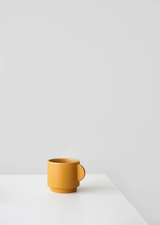 a yellow cup sitting on top of a white table, minimalism, ochre, matt finish, 10k, two