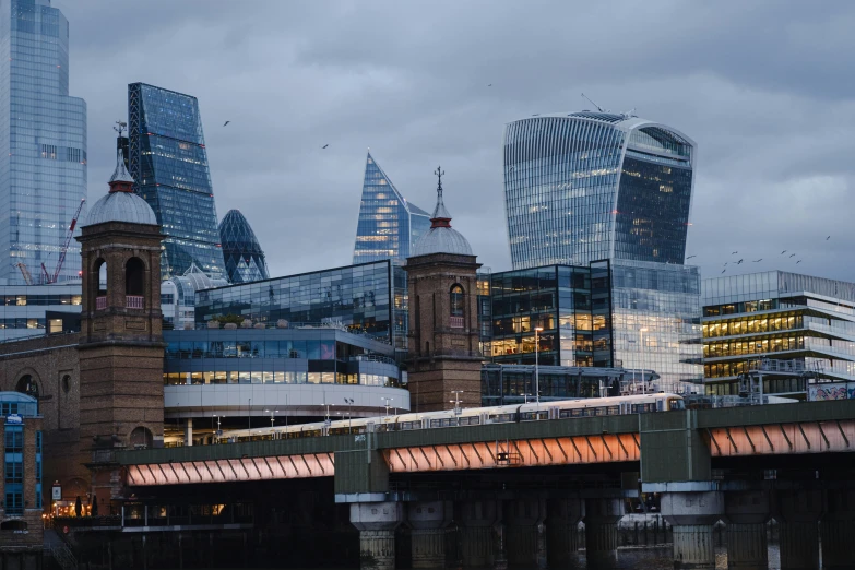 a bridge over a body of water with a city in the background, pexels contest winner, modernism, london architecture, full of glass facades, three towers, brown