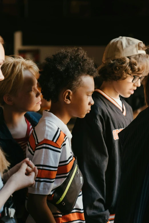 a group of people standing next to each other, by Nina Hamnett, trending on pexels, young boy, looking off to the side, educational, embracing