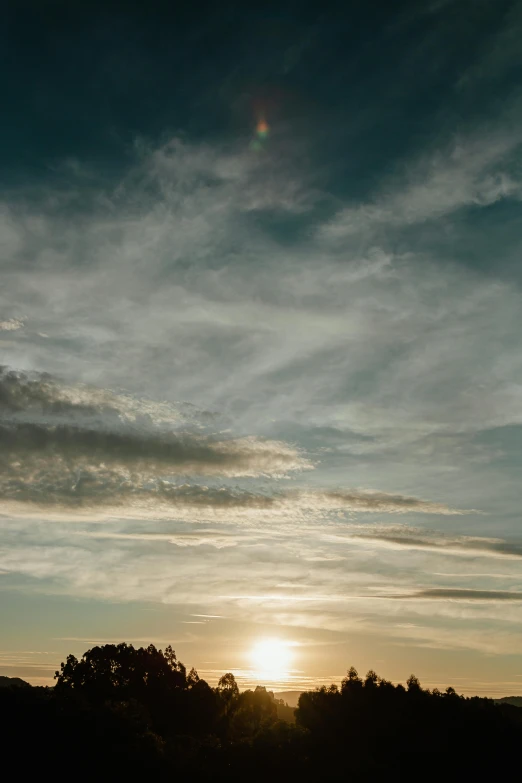 a man flying a kite on top of a lush green field, a picture, by Jesper Knudsen, unsplash, minimalism, sunset panorama, round clouds, hill with trees, sunset photo