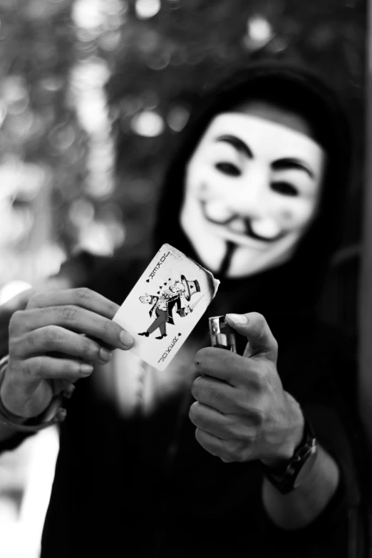 a man wearing a guy mask holding a card, a black and white photo, by Altichiero, hacker, claws are up, revolution, jigsaw