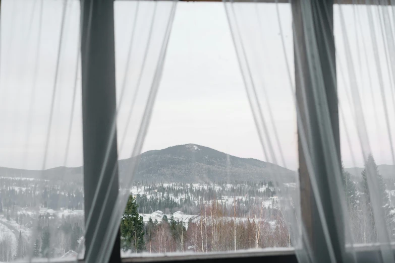 a view of a snowy mountain from a window, inspired by Elsa Bleda, trending on unsplash, fully covered in drapes, kalevala, hotel room, grey