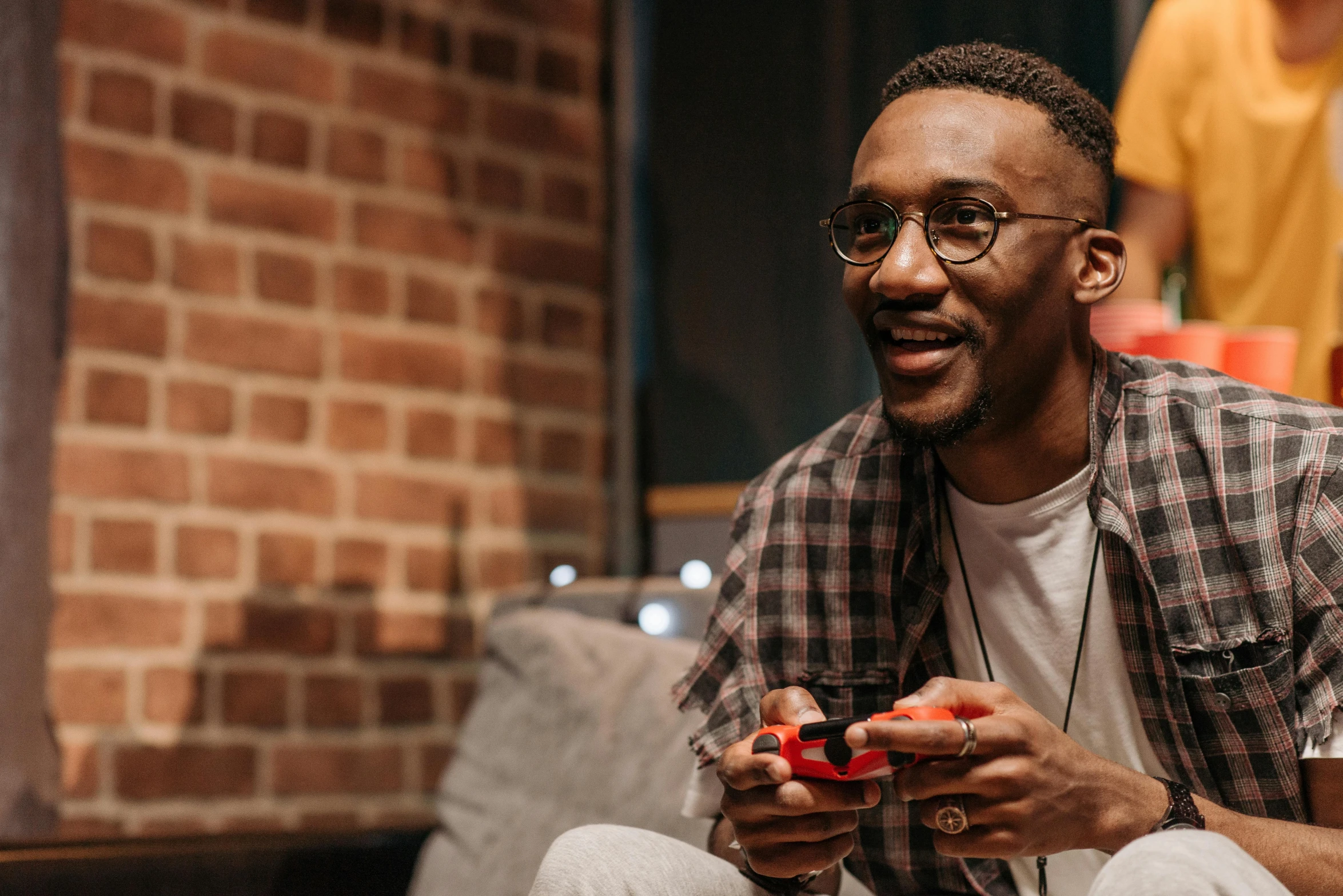 a man sitting on a couch playing a video game, trending on pexels, brown skin man with a giant grin, gordon freeman, high quality wallpaper, ad image