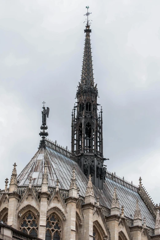 a clock that is on the side of a building, a statue, cathedral ceiling, lead - covered spire, nice slight overcast weather, thin spikes