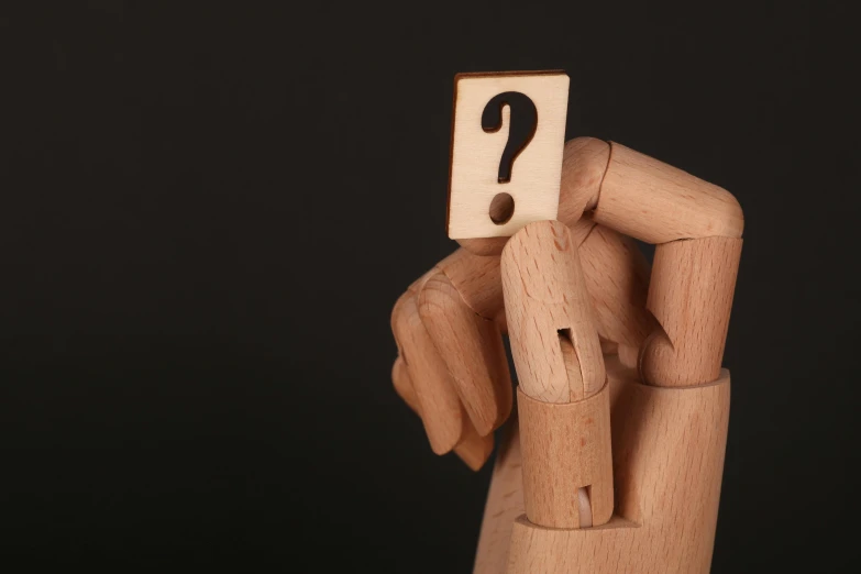 a person holding a wooden block with a question mark on it, by Adam Marczyński, trending on pexels, figuration libre, articulated joints, fan favorite, point finger with ring on it, quixel