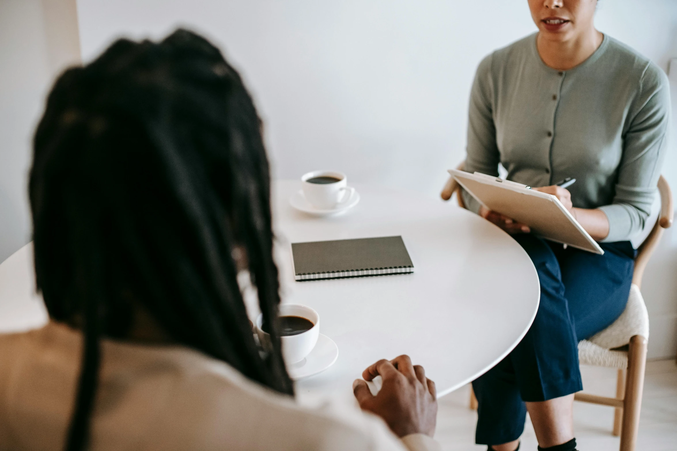 two women sitting at a table talking to each other, trending on unsplash, background image, sitting on a mocha-colored table, someone lost job, npc talking