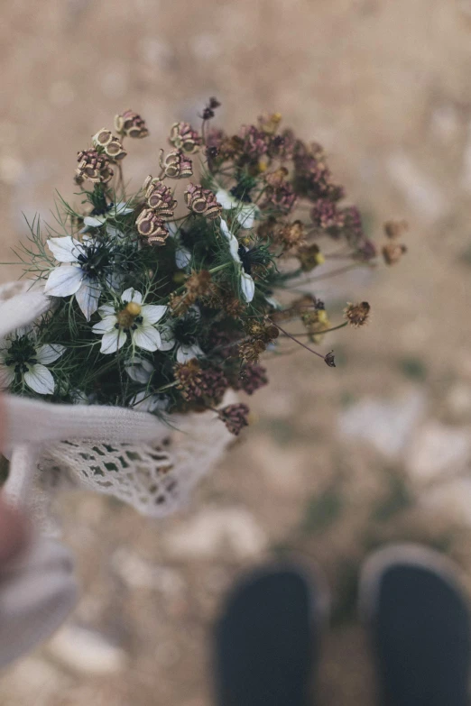 a person holding a bouquet of flowers in their hand, by Jessie Algie, unsplash, intricate details in environment, rugged details, gypsophila, autumnal