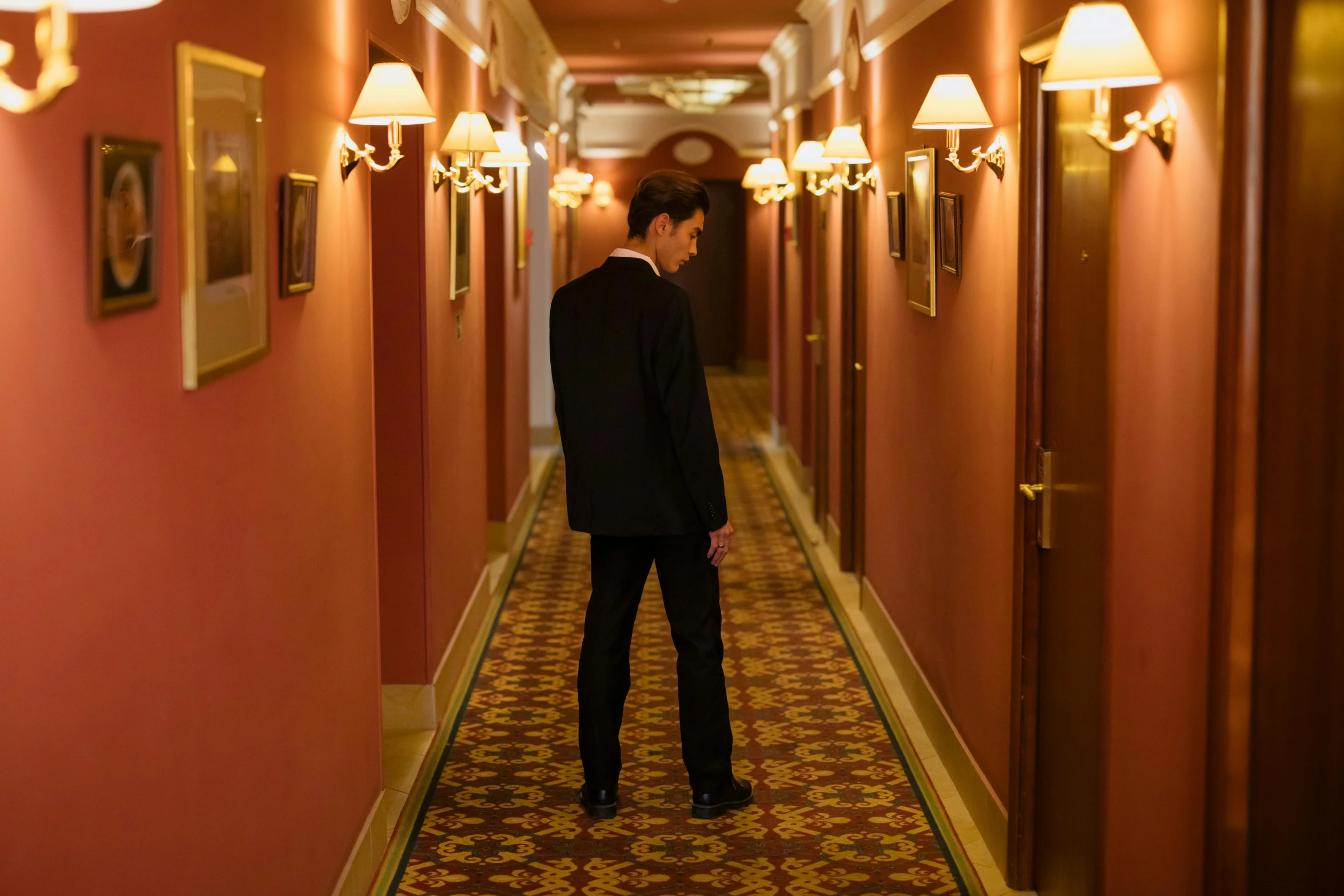 a man in a suit is walking down a hallway, an album cover, inspired by Raymond Leech, unsplash, happening, hotel room, hugh grant, ignant, worried