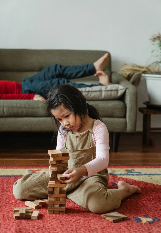 a little girl sitting on the floor playing with wooden blocks, pexels contest winner, caring fatherly wide forehead, asian descent, warm colored furniture, gaming