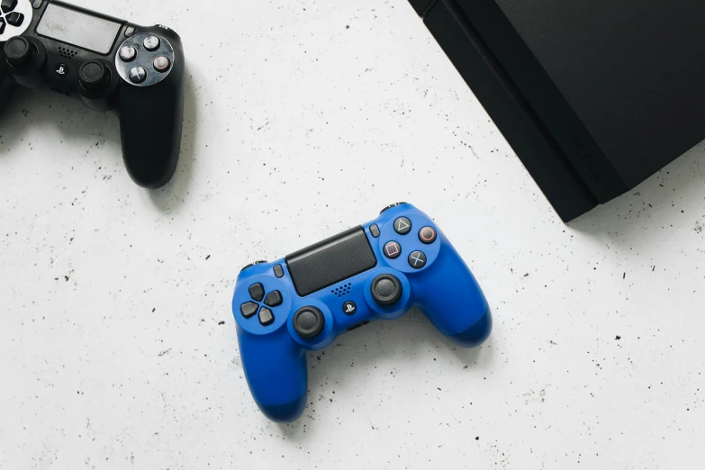 a couple of video game controllers sitting next to each other, unsplash, minimalism, blue and black, on a white table, sony produced, rectangle