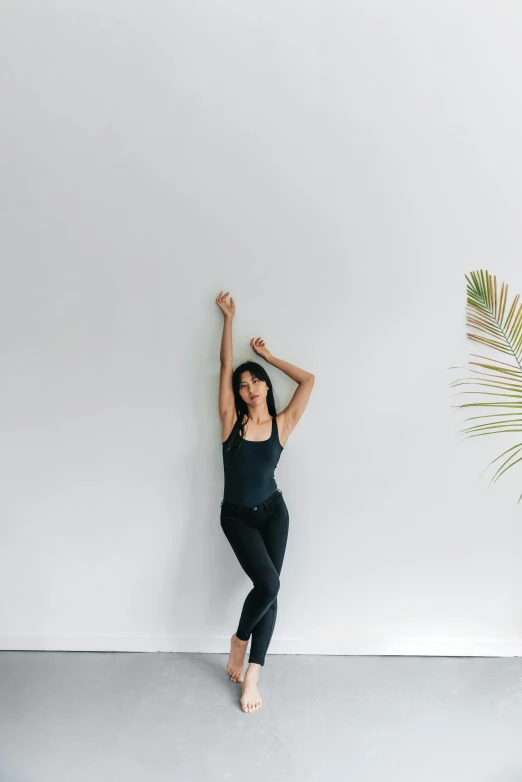 a woman doing a yoga pose in a white room, inspired by Li Di, unsplash, leaning on the wall, standing upright, low quality photo, joy ang