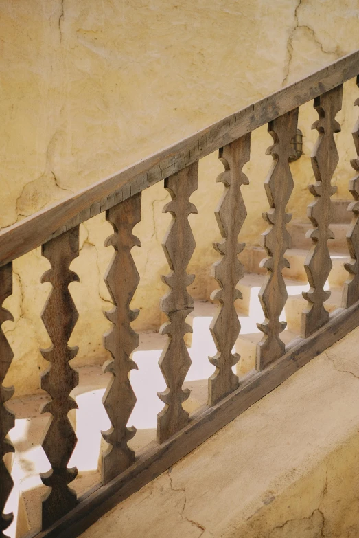 a close up of a railing on a building, inspired by Riad Beyrouti, baroque, interior wood, ochre, timbuktu, old stone steps