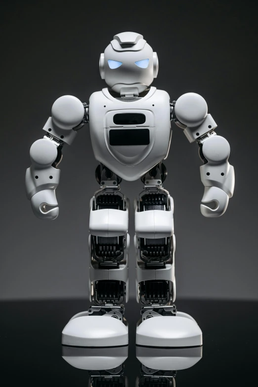 a white robot standing on top of a table, round-cropped, full view of face and body, on a gray background, < full body robot >