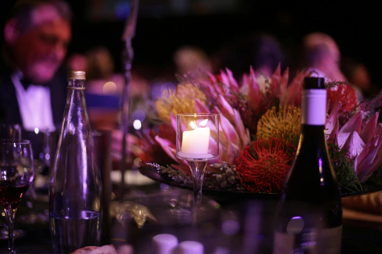 a group of people sitting at a dinner table, lights with bloom, colourful dramatic lighting, holding a candle, purple themed