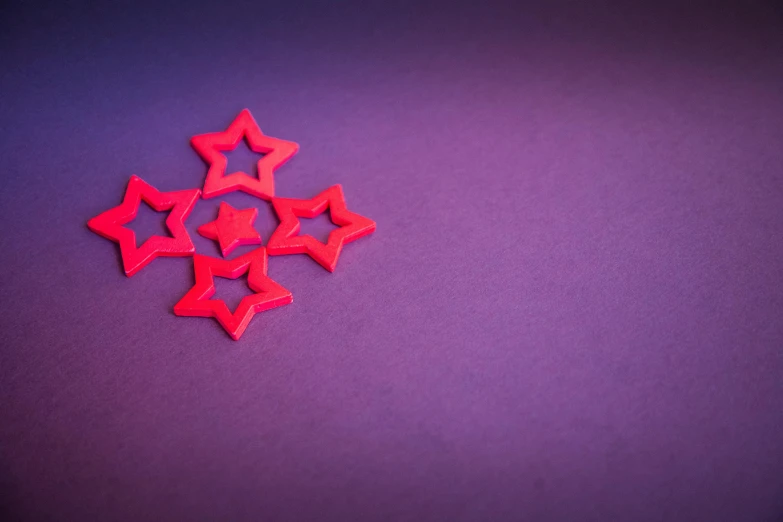 a bunch of red stars sitting on top of a purple surface, by Adam Marczyński, pexels contest winner, minimalism, plasticine, ornament, southern cross, pentagrams