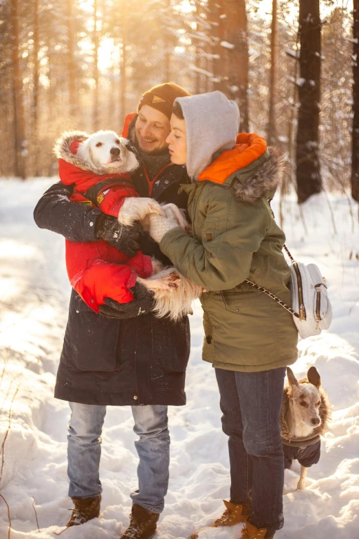 a man and woman holding two dogs in the snow, by Dan Content, shutterstock, romanticism, warm color clothes, instagram picture, thumbnail, holiday