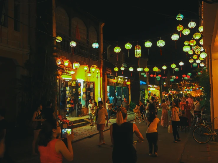 a group of people walking down a street at night, hanging lanterns, hoang lap, light show, instagram post