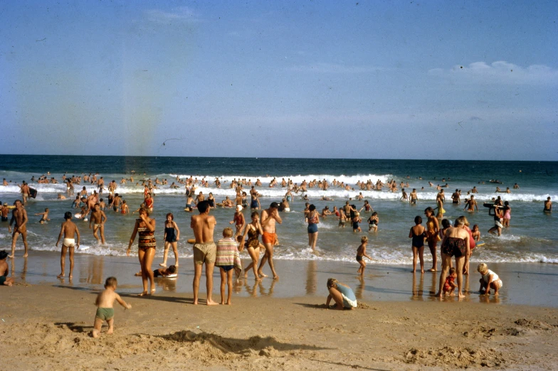 a group of people standing on top of a sandy beach, a colorized photo, by Bertram Brooker, unsplash, bulli, people swimming, crowded place, 15081959 21121991 01012000 4k