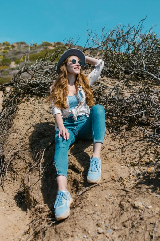 a woman sitting on top of a pile of dirt, wearing blue sunglasses, katherine mcnamara inspired, malibu canyon, profile image