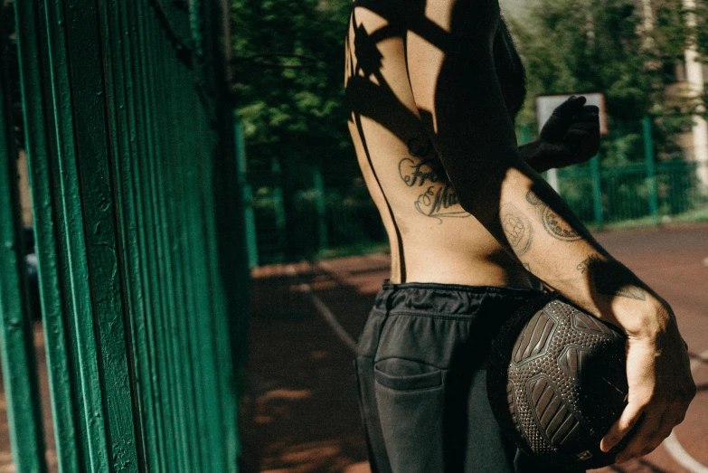 a man standing on a tennis court holding a ball, a tattoo, inspired by Elsa Bleda, trending on pexels, graffiti, holster, playing soccer, in the park, toned derriere