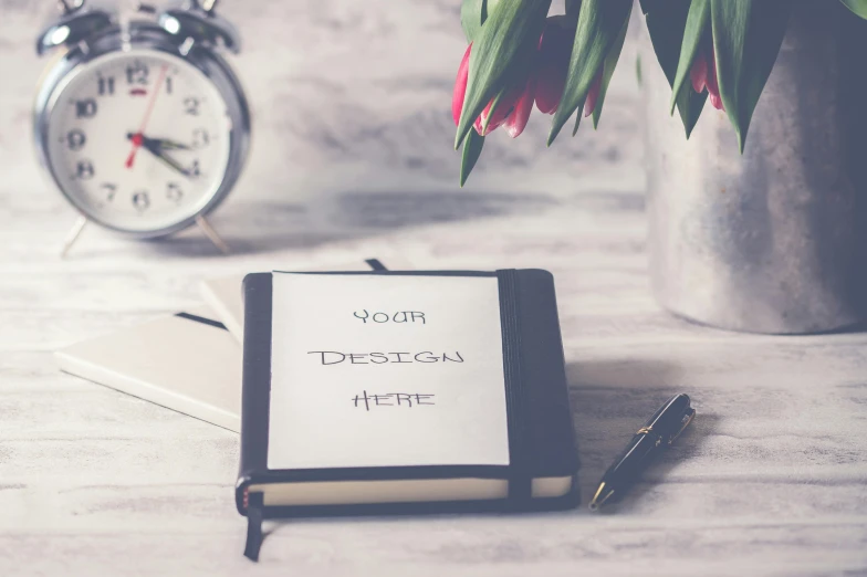 a notepad sitting on top of a table next to a clock, inspired by Johannes van Haensbergen, pexels contest winner, youth, 9 9 designs, books and flowers, website banner