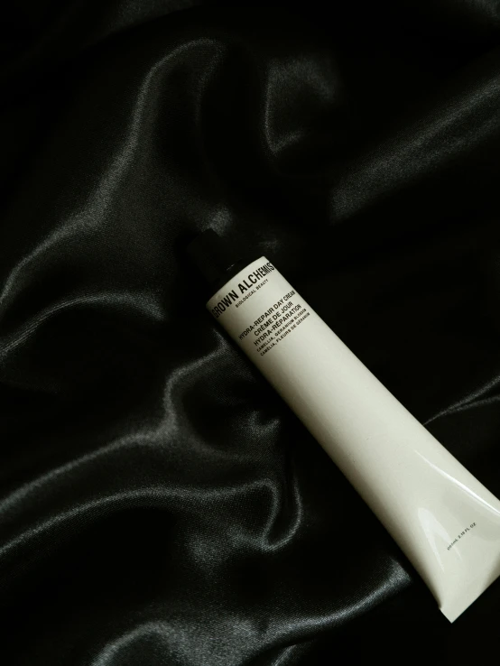 a tube of cream sitting on top of a black cloth, inspired by Marina Abramović, unsplash, photorealism, palm body, low quality photo, japanese collection product, aquiline nose!!