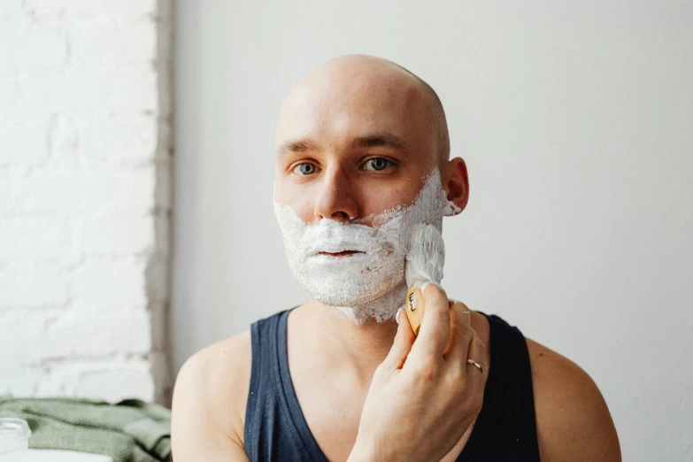 a bald man shaving his face with a razor, by Julia Pishtar, trending on pexels, square face, covered in white flour, lachlan bailey, 40 years old women