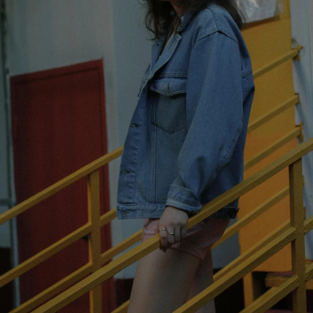 a woman standing at the top of a flight of stairs, inspired by Elsa Bleda, pexels contest winner, photorealism, denim jacket, exposed thighs, lorde, teenager girl