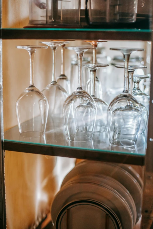 a glass shelf filled with wine glasses and plates, large glasses, up close, mirrors, item